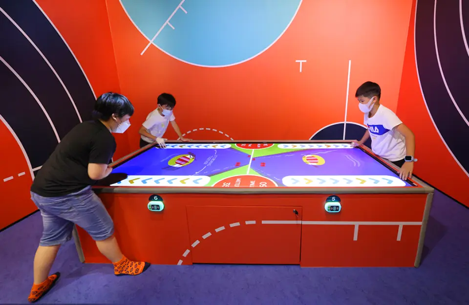 香港西部のSooper Yoo大規模屋内遊び場で、家族がインタラクティブなエアホッケーテーブルでテクノロジースポーツに挑戦し、家族の楽しい時間を過ごしています。