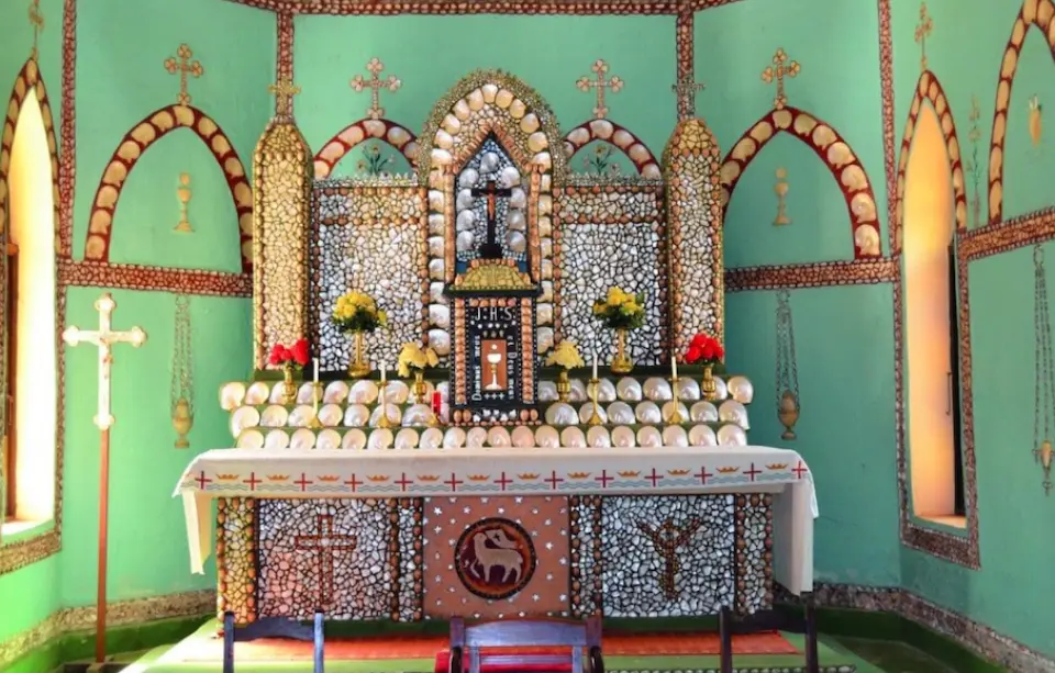 Interior of the Sacred Heart Church in Australia's Beagle Bay Aboriginal Community, featuring an altar and walls intricately decorated with unique shells, showcasing profound cultural art and local Aboriginal faith.