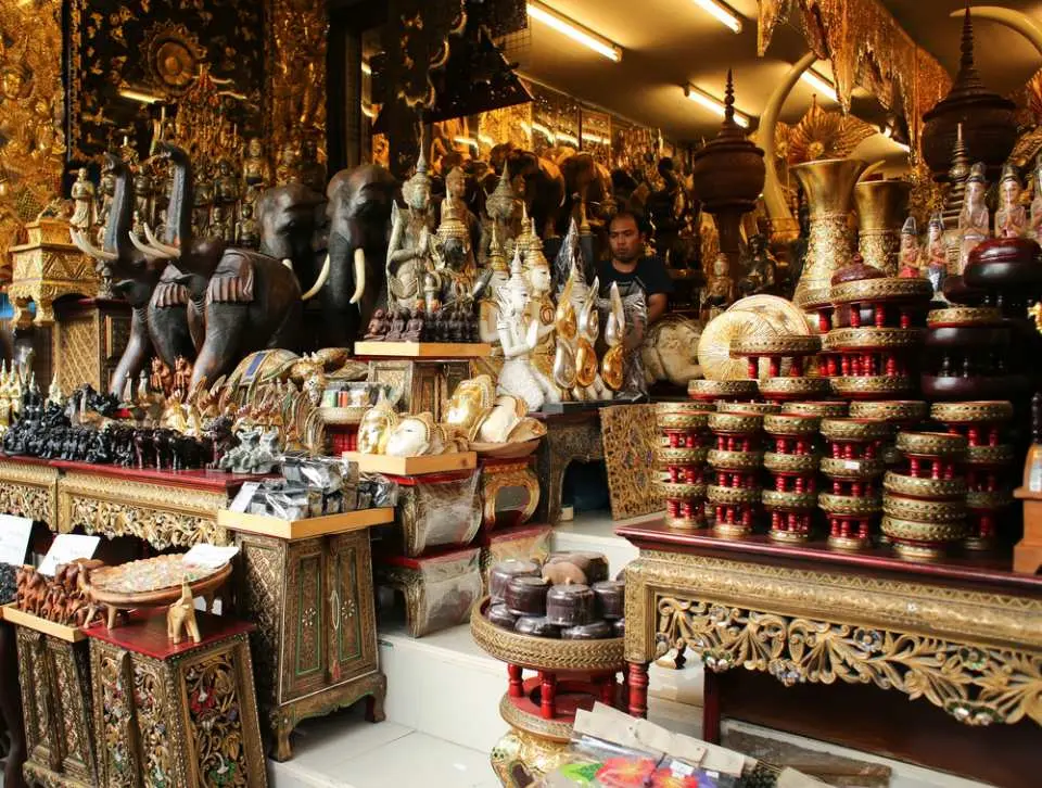 Một gian hàng tại Chợ cuối tuần Chatuchak đầy ắp các sản phẩm thủ công mỹ nghệ Thái Lan tinh xảo, bao gồm voi gỗ chạm khắc, tượng Phật và đồ trang trí mạ vàng lộng lẫy.