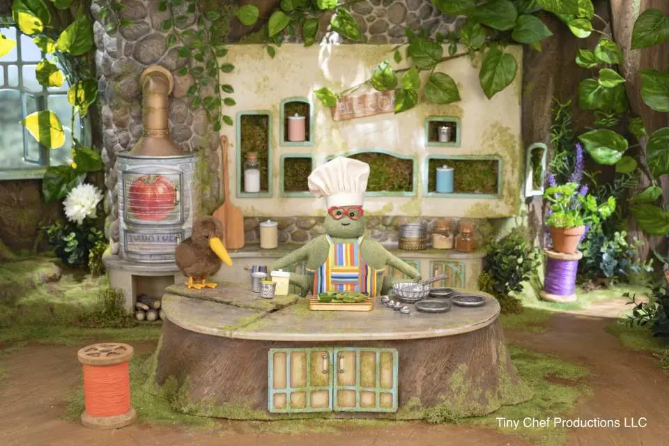 A delightful frog chef puppet alongside a kiwi bird in a whimsical miniature kitchen, part of a special, imaginative exhibition at California Academy of Sciences.