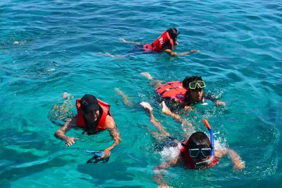 Tourists snorkeling in the vibrant, clear waters of Ao Lah bay, exploring colorful marine life during the Racha Island and Coral Island speedboat tour from Phuket.