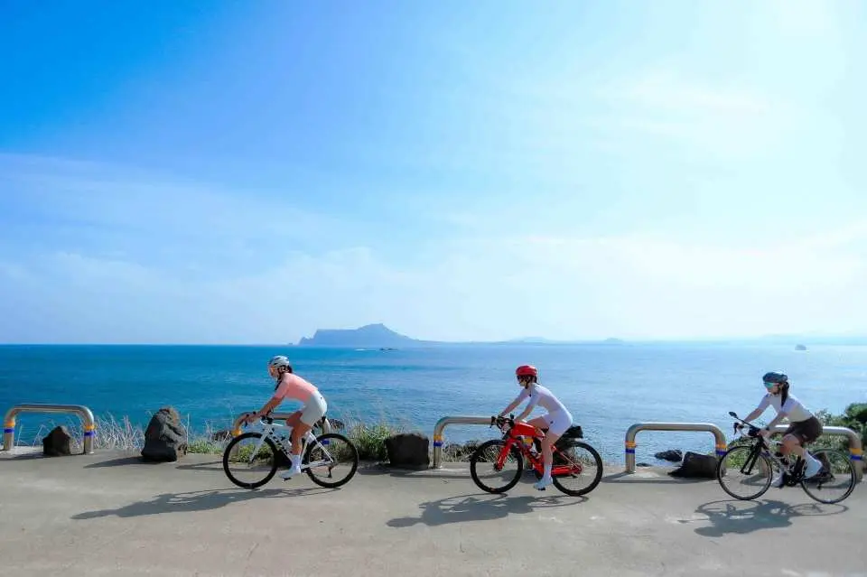【島中之島：牛島，慢下來遇見濟州的湛藍靈魂】含渡輪船票+電動自行車(每人一台)：如果說濟州島是韓國的珍珠，那麼「牛島」就是那顆珍珠上最閃耀的光芒。因島形像是一頭臥牛而得名，這裡沒有城市的喧囂，只有風聲、浪濤聲，以及專屬於海島的平靜。  搭上渡輪，僅需 15 分鐘，就能抵達這座充滿活力的「島中之島」。在這裡，你可以騎著電動單車隨心停靠，在純白的珊瑚沙灘上發呆，或是品嚐一口在地濃郁的牛島花生冰淇淋。牛島的藍，是有層次的——從淺灘的Tiffany綠到深海的寶石藍，每一眼都是足以珍藏的明信片風景。*圖片僅為示意，腳踏車款式依現場提供為主*