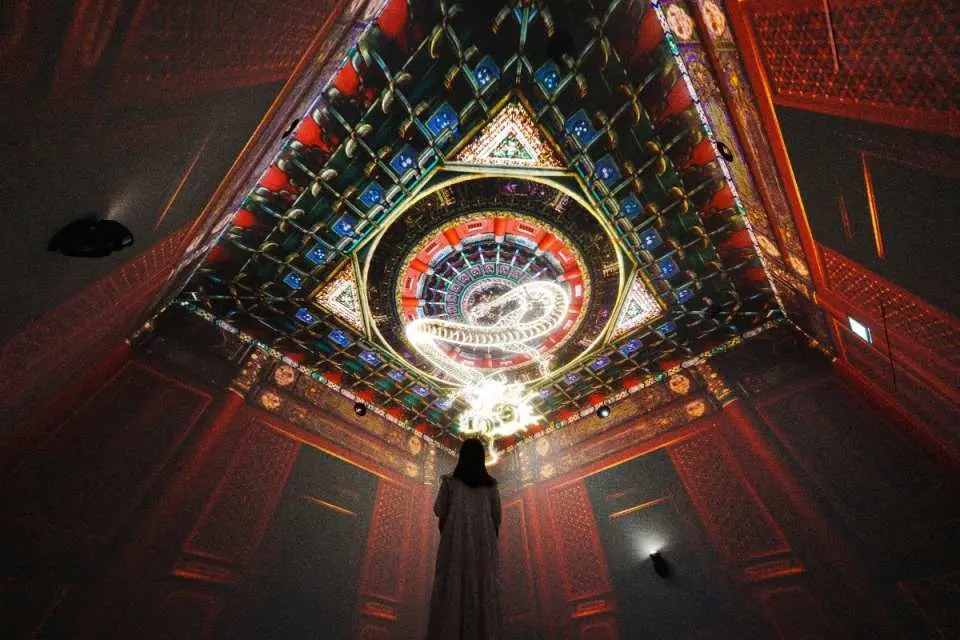 An immersive experience at a Hong Kong Palace Museum special exhibition, where visitors are surrounded by dazzling light projection art, appreciating the beauty of ancient cultures.