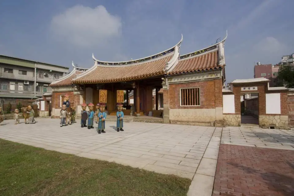A panoramic exterior view of Kaohsiung's grand Fengyi Academy, showcasing its traditional architectural complex and spacious courtyard under a clear sky, a significant cultural landmark.
