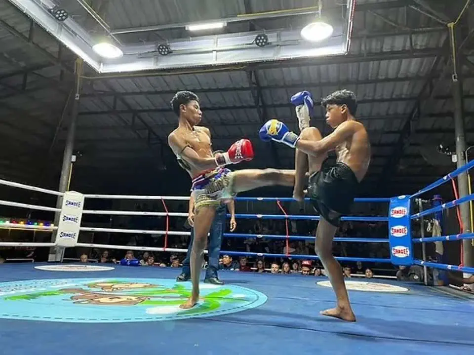 Two skilled Muay Thai fighters in the ring at Lanta Boxing Stadium in Koh Lanta, demonstrating powerful kicks and authentic Thai boxing techniques during a live match.