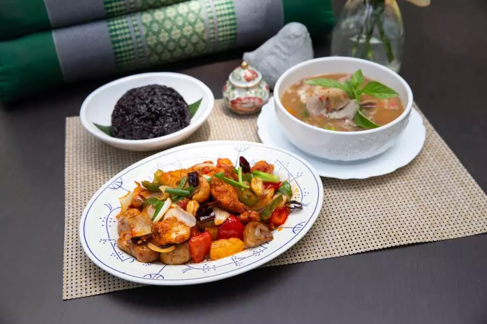 Bangkok Raweekanlaya wellness cuisine: a delicious Thai curry, flavorful black rice, and fresh stir-fried vegetables, blending gourmet taste with healthy living.