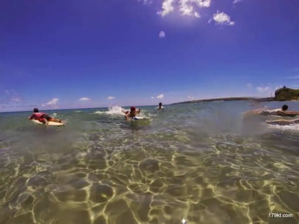 學員們在墾丁清澈的淺海中學習衝浪，專業教練在旁指導，準備體驗駕馭浪板的樂趣。
