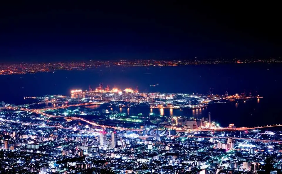 六甲山望見神戶港口城市璀璨的夜景，海灣上燈火通明，猶如散落的鑽石，展現神戶作為國際港都的獨特魅力。