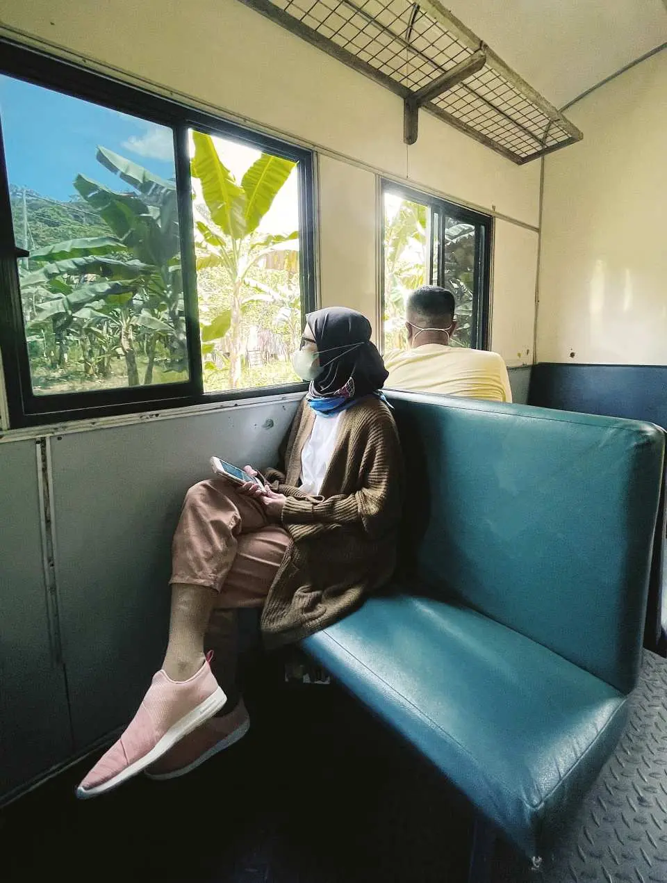 Inside a traditional train carriage at Tenom Station in Sabah, a passenger looks out the window, enjoying the scenic journey en route to the Padas River for an unforgettable rafting experience.
