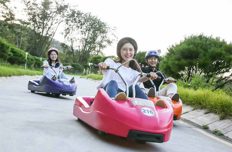 遊客在江華島享受 LUGE 斜坡滑車的樂趣，戴著安全帽沿著仁川首爾近郊最長滑道俯衝而下，體驗刺激又安全的戶外活動。