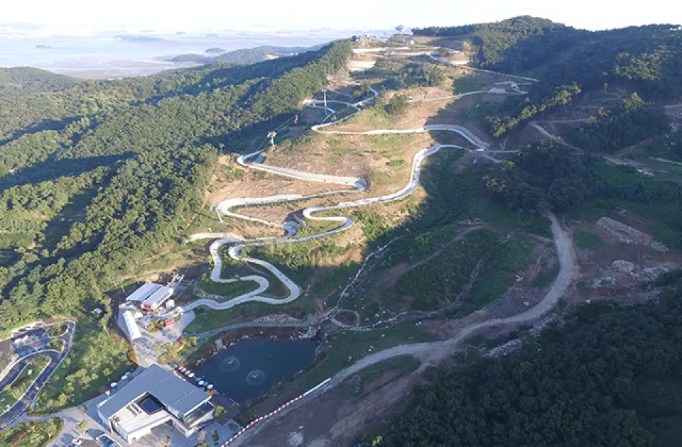 江華島 LUGE 斜坡滑車與纜車園區的廣闊全景，展現仁川首爾近郊綠意盎然的山坡上，蜿蜒而下的全韓國最長滑道設計。