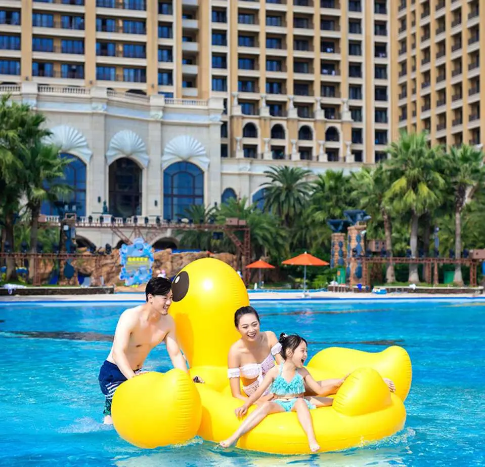一家三口在珠海長隆橫琴灣水世界，興奮地乘坐巨型黃色小鴨造型充氣船，盡情享受泳池樂趣。