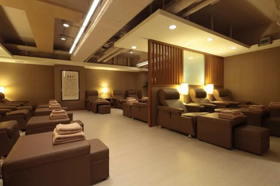 Multi-functional massage area at Zaichun Health & Life Hall in Taipei, featuring comfortable foot massage chairs, wooden partitions, and warm lighting to create a private, relaxing space for individuals or groups.