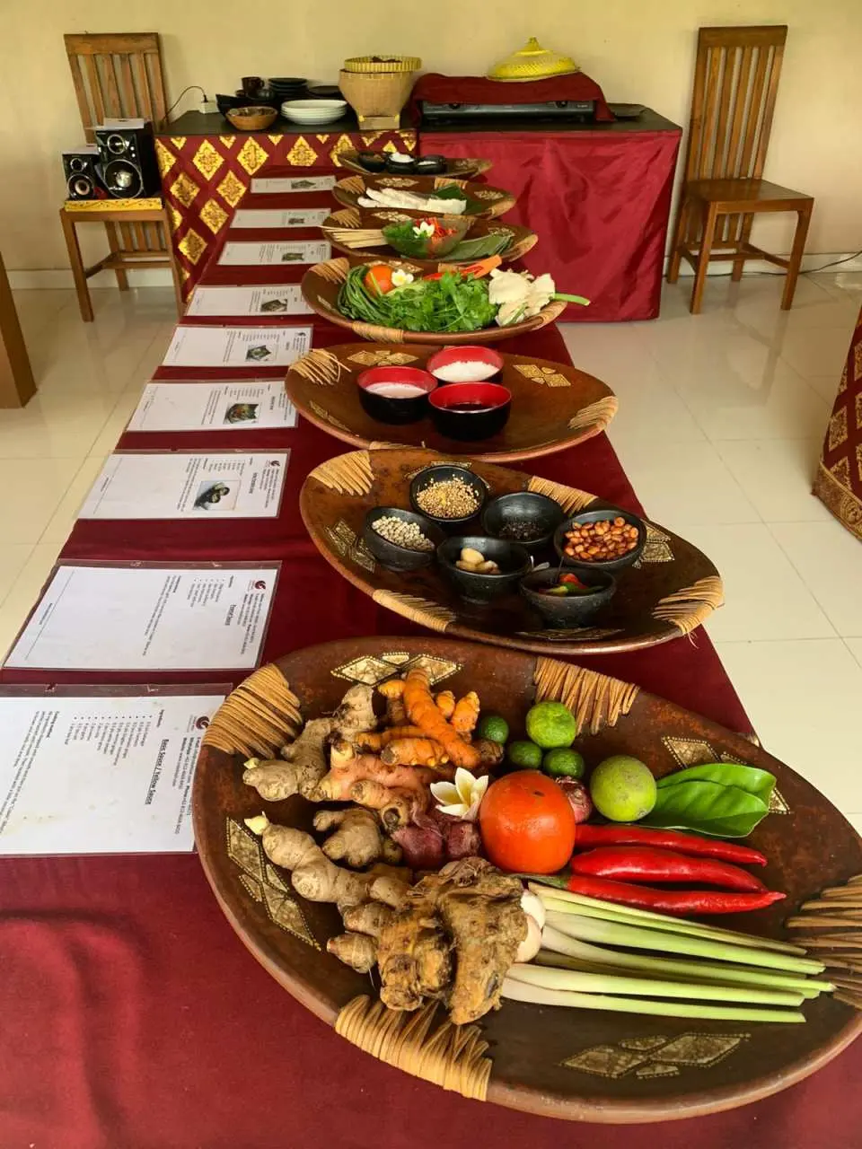 A long table at the Ubud Balinese cooking class, laden with an abundant variety of fresh spices, vibrant vegetables, and prepared traditional dishes, showcasing rich local culinary culture.