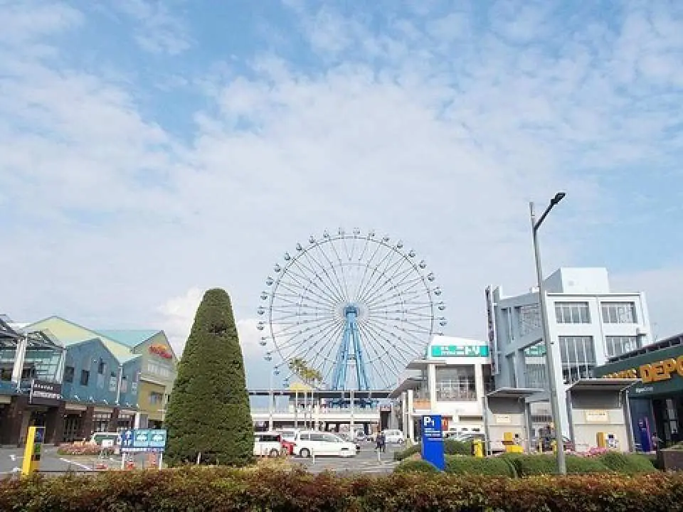 The prominent Ferris wheel of Fukuoka's Marinoa City rises above modern shopping complexes and bustling streets, offering a vibrant urban and entertainment scene.