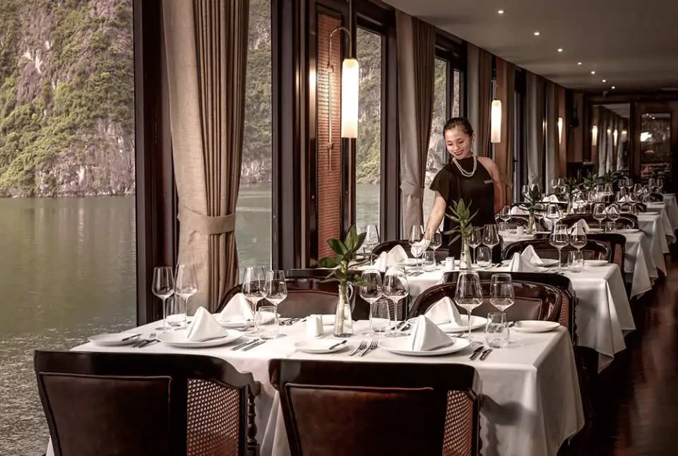 Spacious luxury cabin on the Ambassador cruise, featuring a comfortable double bed and a private balcony offering stunning sea views of Halong Bay.