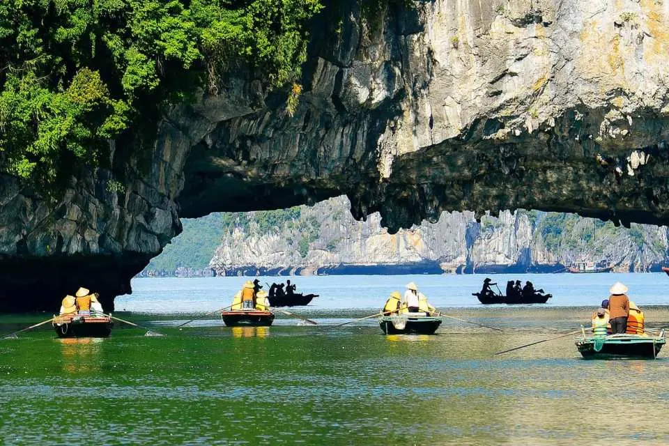 Halong Bay small boat exploration, with visitors paddling through limestone grottoes and lagoons, experiencing the natural wonders up close.