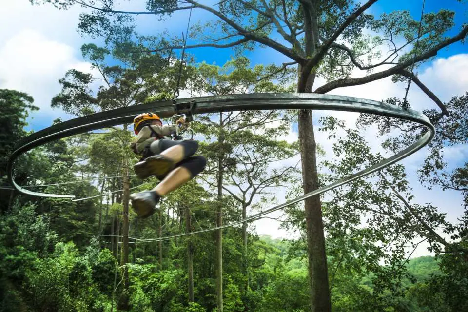 An adventurer speeding on a unique circular zipline in Chiang Mai, experiencing the exhilarating thrill of soaring and circling through the tropical jungle of Thailand.