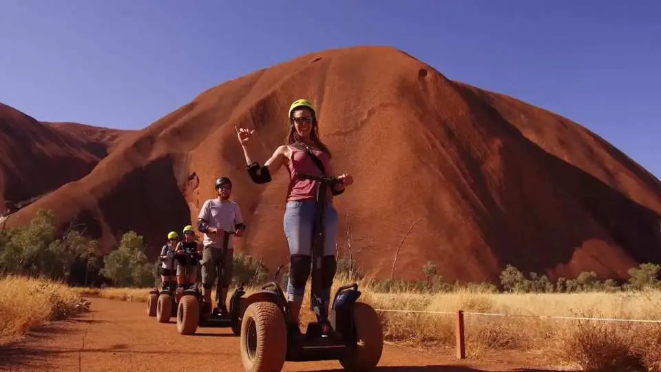 Group exploring Uluru's base on Segways, enjoying the unique adventure and scenic beauty of the iconic Australian desert landscape.