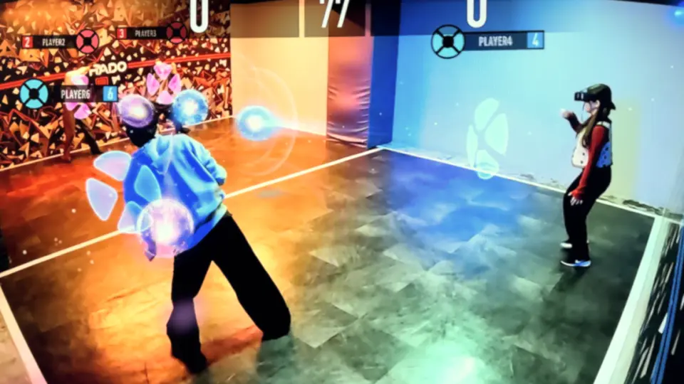 Two players in RED° TOKYO TOWER's XR arena engage in a virtual combat game, with light and shadow projecting energy spheres and battle effects, experiencing Japan's largest AR/VR esports experience.
