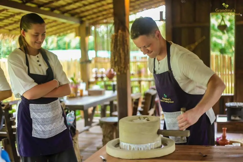 At a Chiang Mai Northern Thai cooking school, students experience grinding rice flour or wheat flour with a traditional stone mill, a unique step for making Thai desserts or noodles.