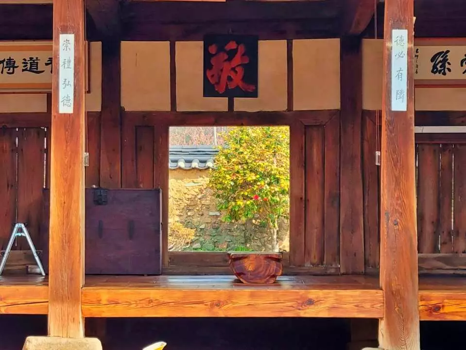 An interior view of a traditional Hanok house, possibly Baekbullo House or in Otgol Village, Daegu, highlighting its classic wooden structure and the serene green view outside, evoking Joseon-era charm.
