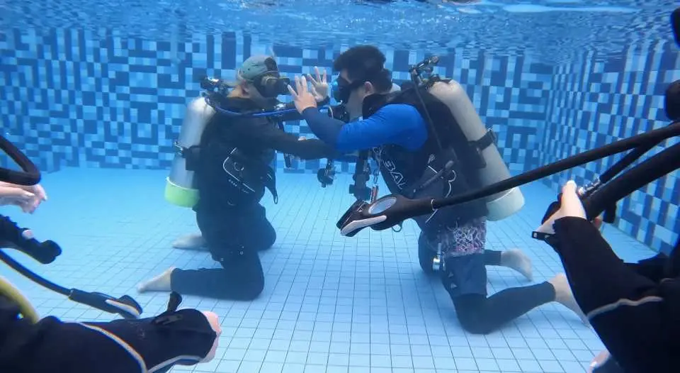 PADI OW初級オープンウォーターコースの生徒2名が、緑島のプールトレーニングでダイビング装備を装着し、オープンウォーターダイビングに備えてスキルを練習しています。