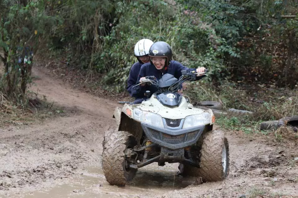 タイのチェンマイX-Centreで、2人の観光客がATVを運転して泥だらけで滑りやすいジャングルの小道を通り抜け、起伏の多いオフロードの挑戦と楽しさを満喫しています。