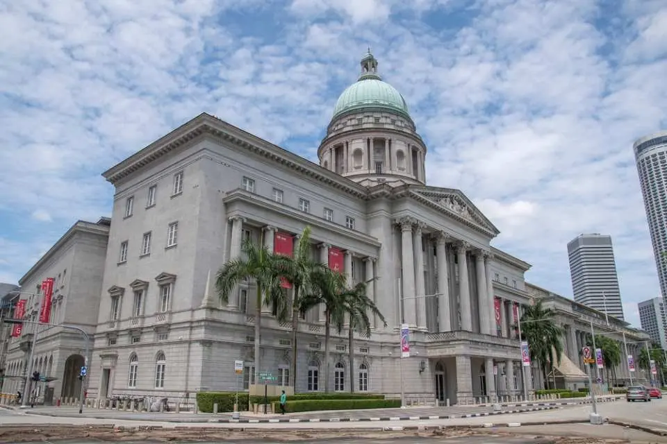 The majestic facade of Singapore's National Gallery, featuring its green dome, grand columns, and surrounding palm trees, an important historical landmark on the audio-guided walking tour.
