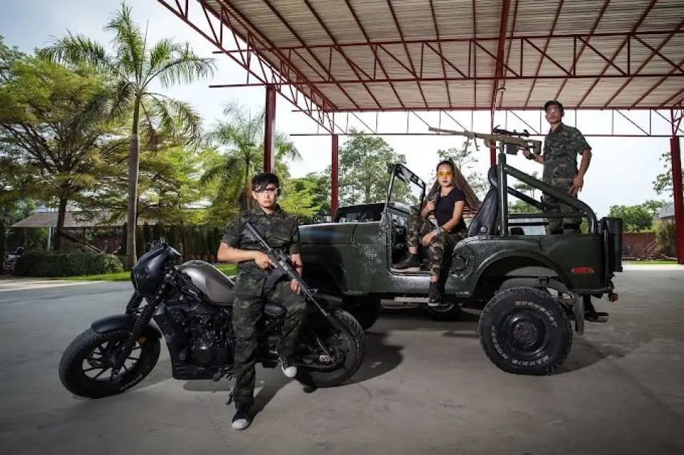 Customers in camouflage pose with firearms, a motorcycle, and a jeep at Black Water King Shoot Club Pattaya, capturing the thrilling outdoor shooting experience.