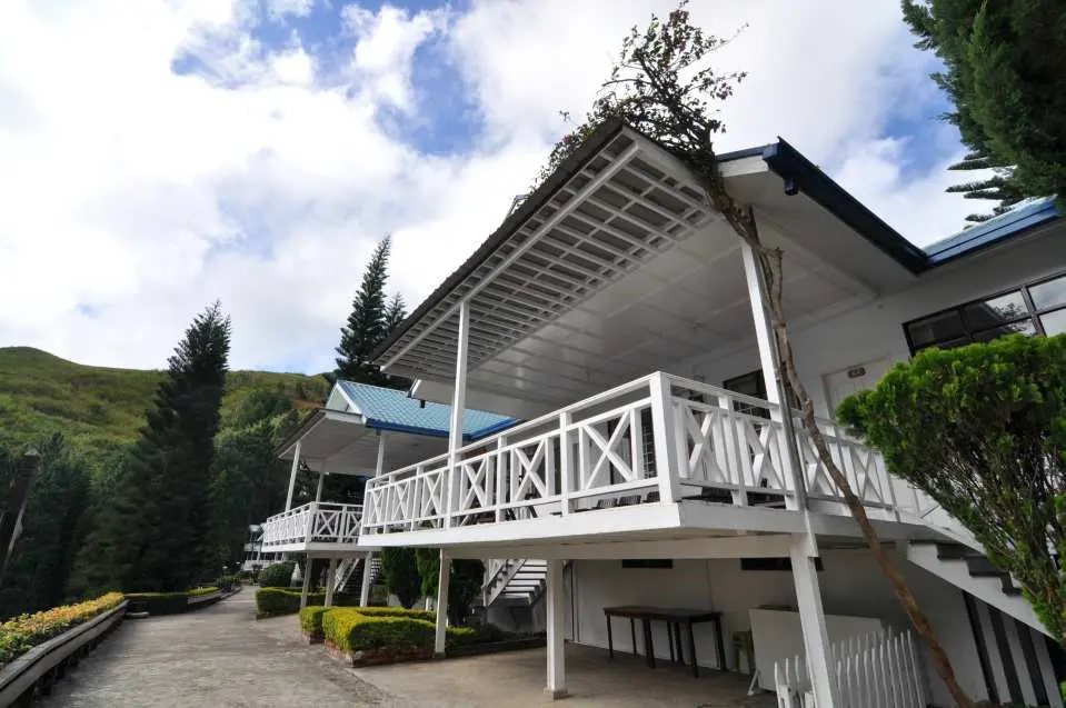 京那巴魯山舒適的高地度假村住宿，白色建築設有陽台，周圍環繞綠樹，為沙巴登山者提供放鬆空間。