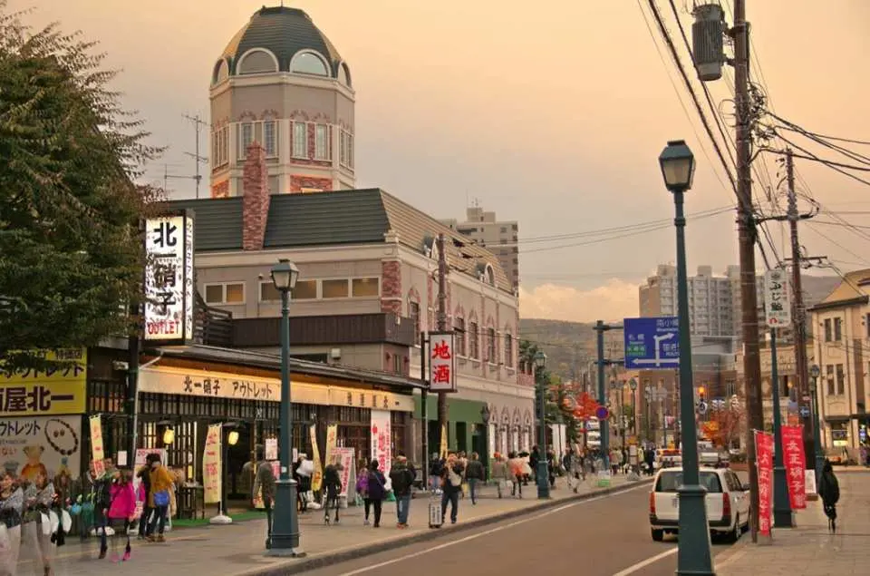 Otaru's charming streetscape in Hokkaido at dusk, with European-style buildings illuminated, visitors strolling on a private guided tour, soaking in the city's romantic ambiance.