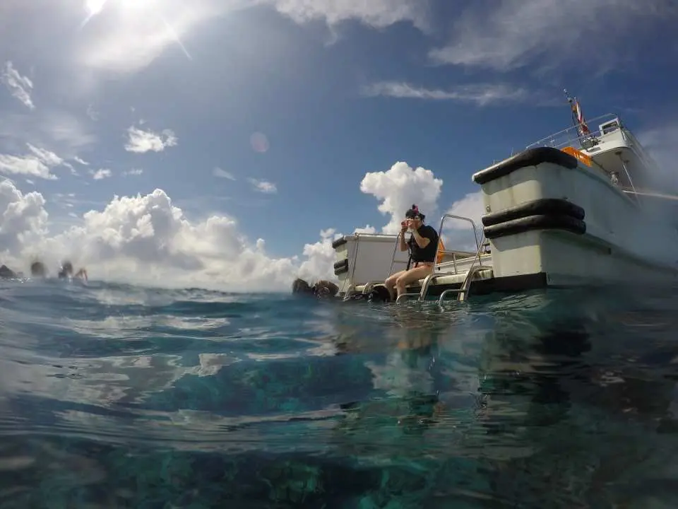 A snorkeler sits on a boat ladder, ready for or just finished exploring the beautiful waters of Okinawa's Kerama Islands, departing from Chatan.