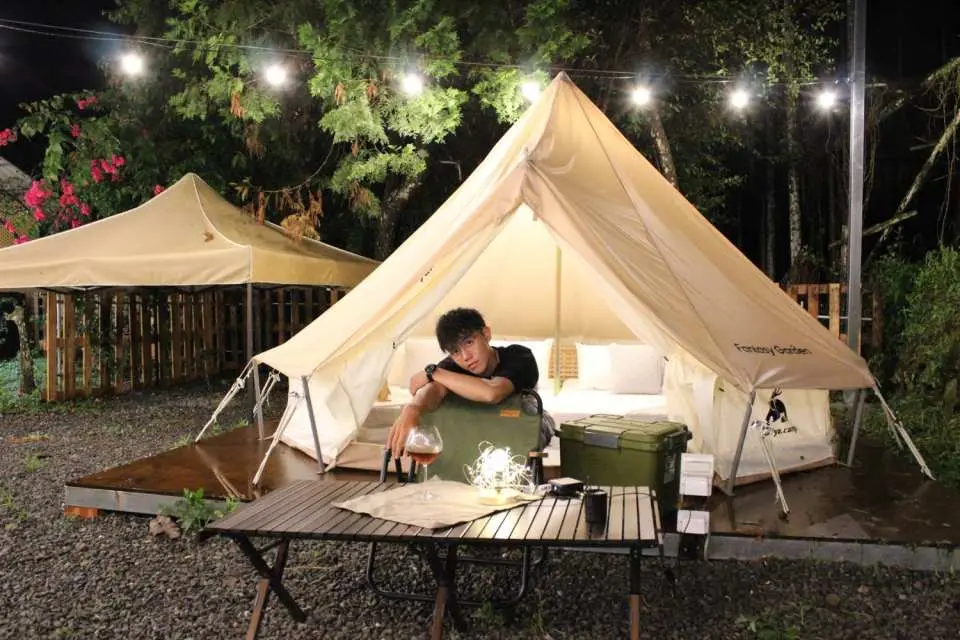 南投光隅免裝備露營體驗，遊客在鐘型帳篷前享受夜晚，戶外桌擺設飲品，體驗悠閒放鬆的露營樂趣。