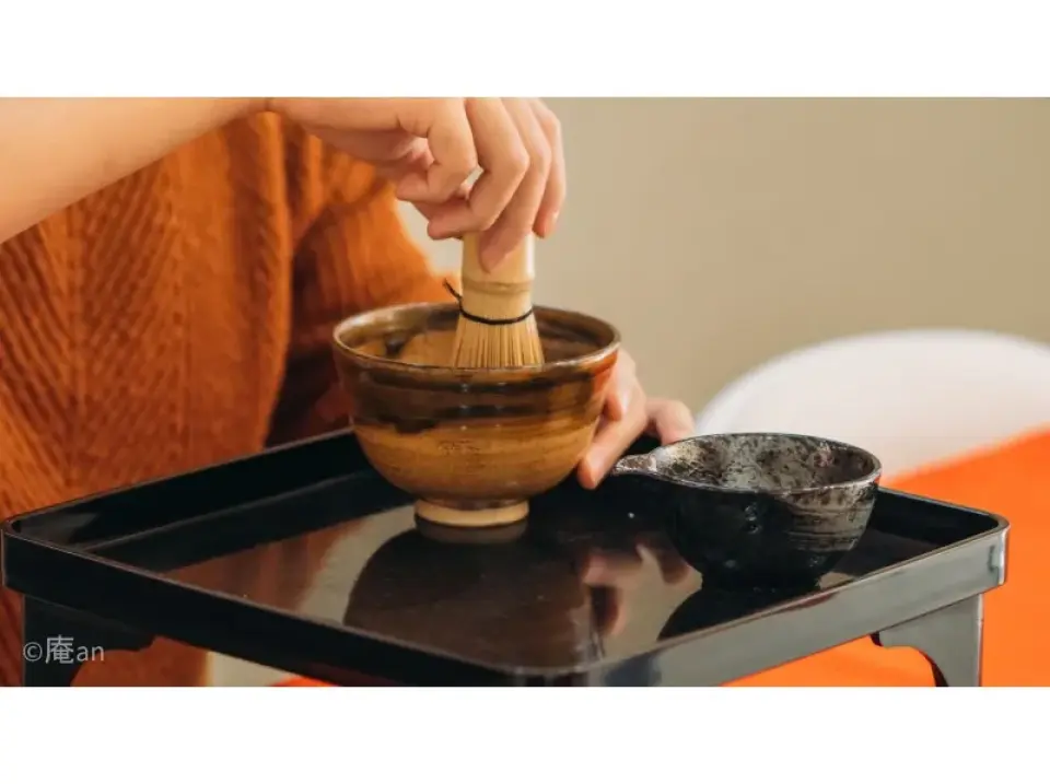 Participating in a Kyoto matcha making experience, learning to whisk special single-origin matcha in a beautiful ceramic bowl with a bamboo whisk.