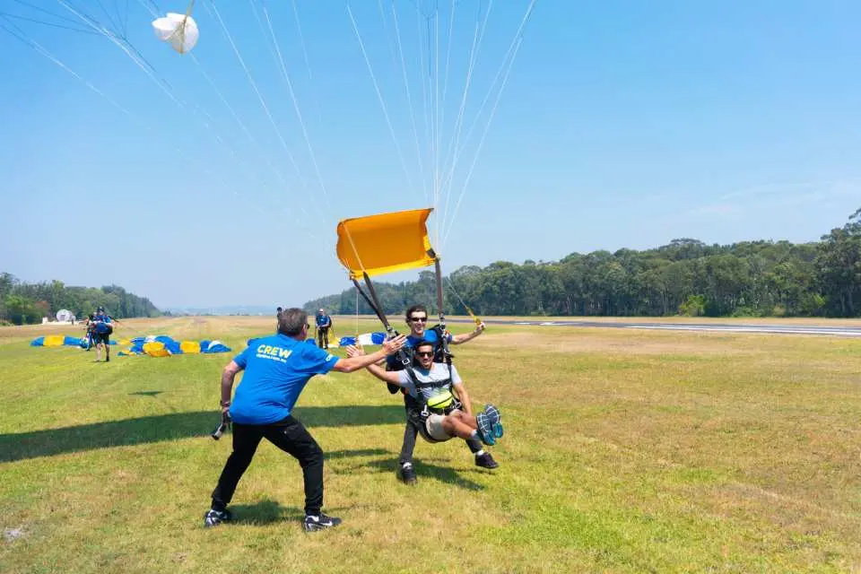 プロのインストラクターの助けを借りて、ニューカッスルに安全に着陸するタンデムスカイダイバー。オーストラリア、ニューサウスウェールズ州での忘れられないスカイダイビング体験が終了。