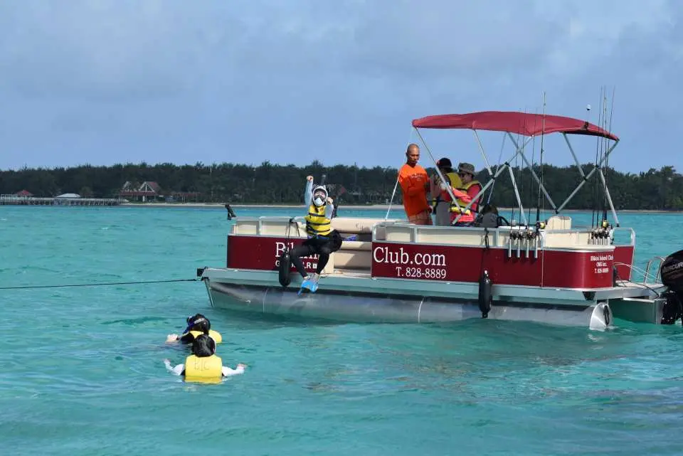 Guests eagerly entering the clear turquoise waters from the private pontoon boat, ready for exciting snorkeling and swimming adventures on their Guam tour.