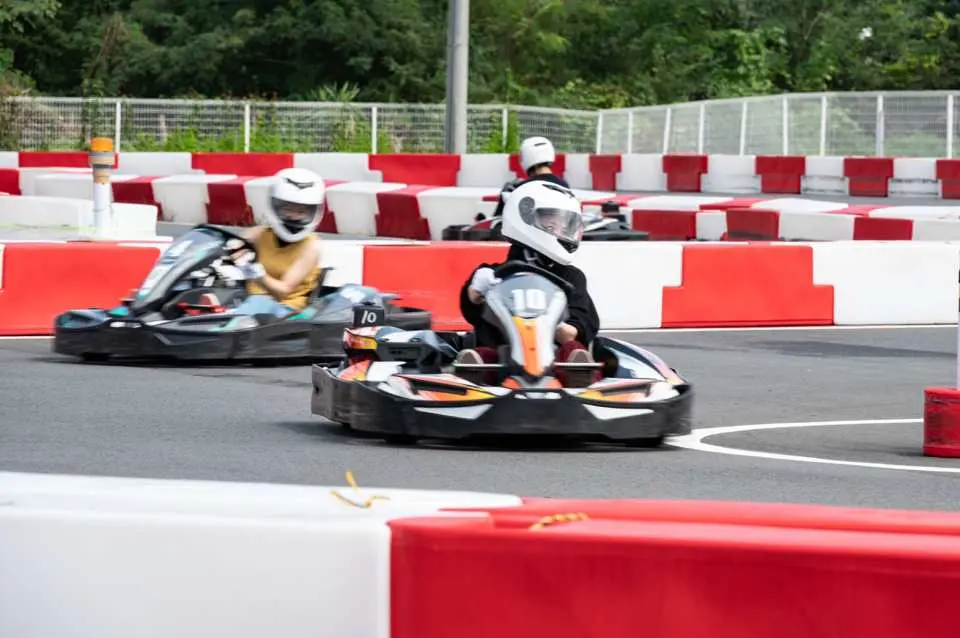 Two drivers expertly navigate a sharp curve on the Osaka Maishima karting track, experiencing the speed and precise handling of SodiKart go-karts during a thrilling race.