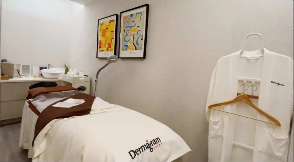 An elegant treatment room at Dermagram Institut Causeway Bay, Hong Kong, with a comfortable massage bed, artistic decor, and a bathrobe, offering a premium private lymphatic massage or facial experience.