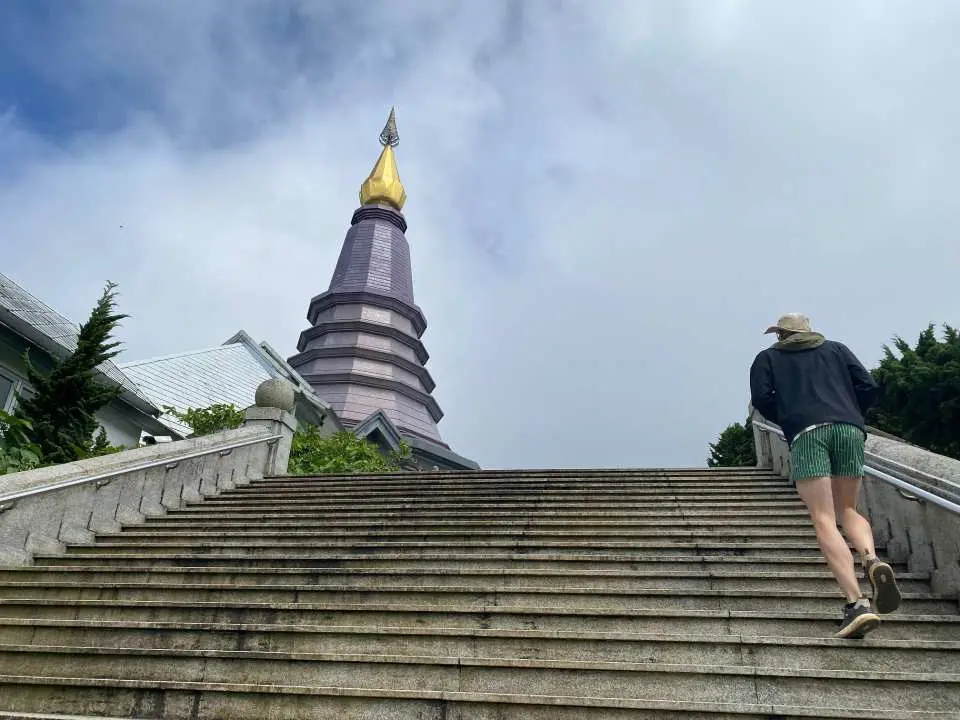 On top of Doi Inthanon, a visitor climbs the majestic stairs leading to the grand Nabhapolbhumisiri Royal Pagoda, experiencing its solemn and sacred ambiance.