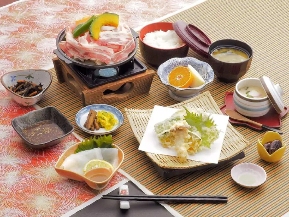 A hearty Japanese shabu-shabu set meal with sashimi and various delicate side dishes, showcasing potential lunch or dinner options for the Kyushu Kuju Kurokawa day tour.