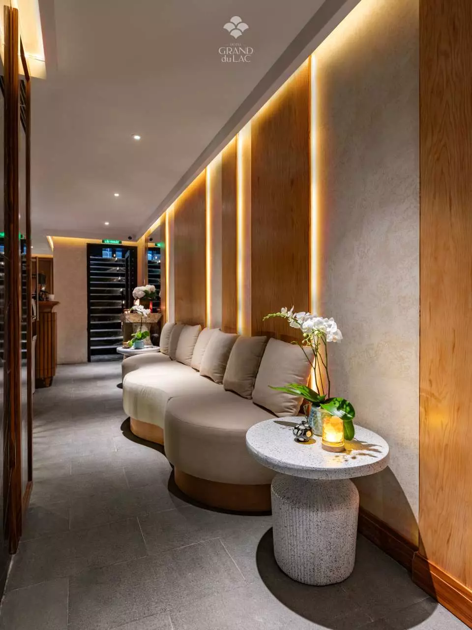 Modern luxury lounge area at La Maison Grand Spa in Hanoi, featuring elegant curved sofas, warm accent lighting, and sophisticated decor for a tranquil welcome.