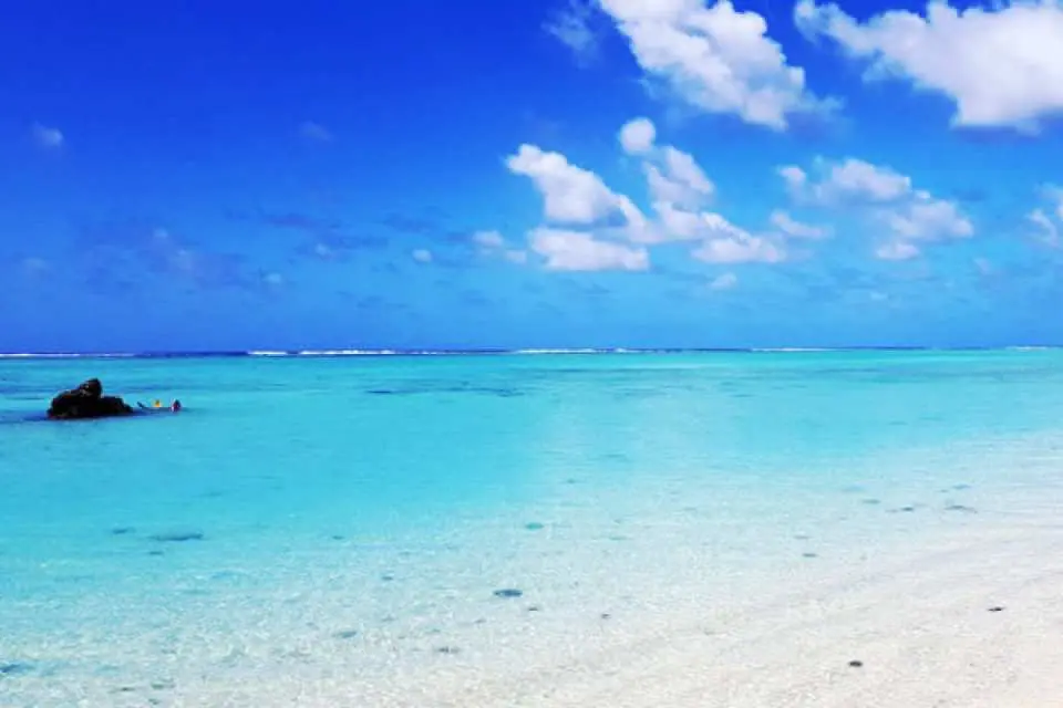 사이판 파우파우 비치의 깨끗한 백사장과 투명한 에메랄드빛 바다. 반나절 투어에서 평화로운 자연 휴식을 즐기세요.