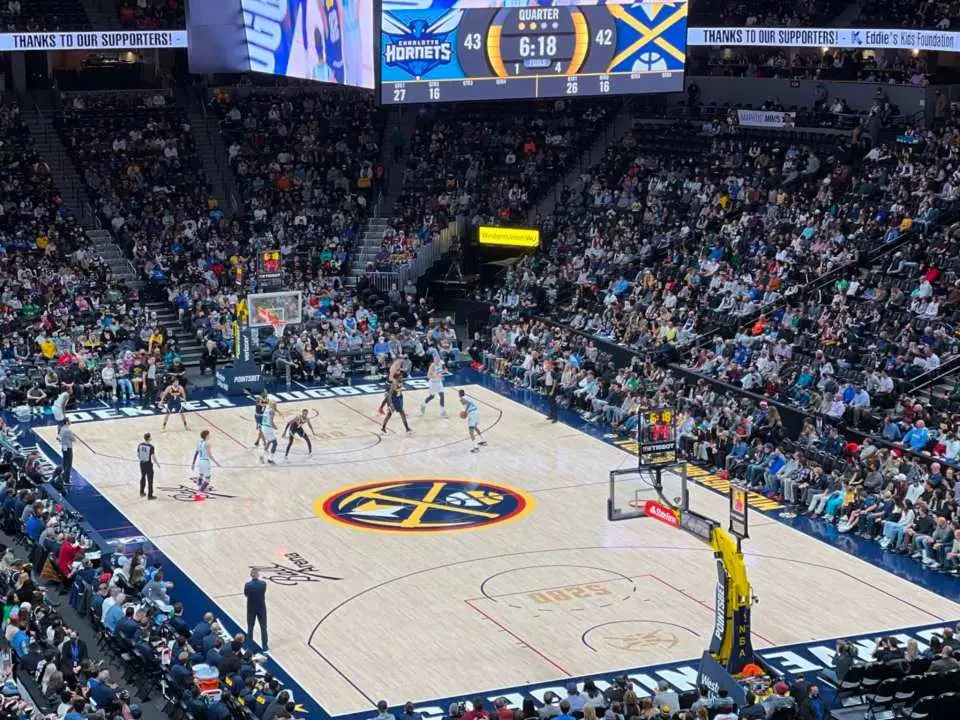 A close-up view of an intense NBA Denver Nuggets basketball game in action at Ball Arena, with players on the court and the scoreboard displaying real-time scores.