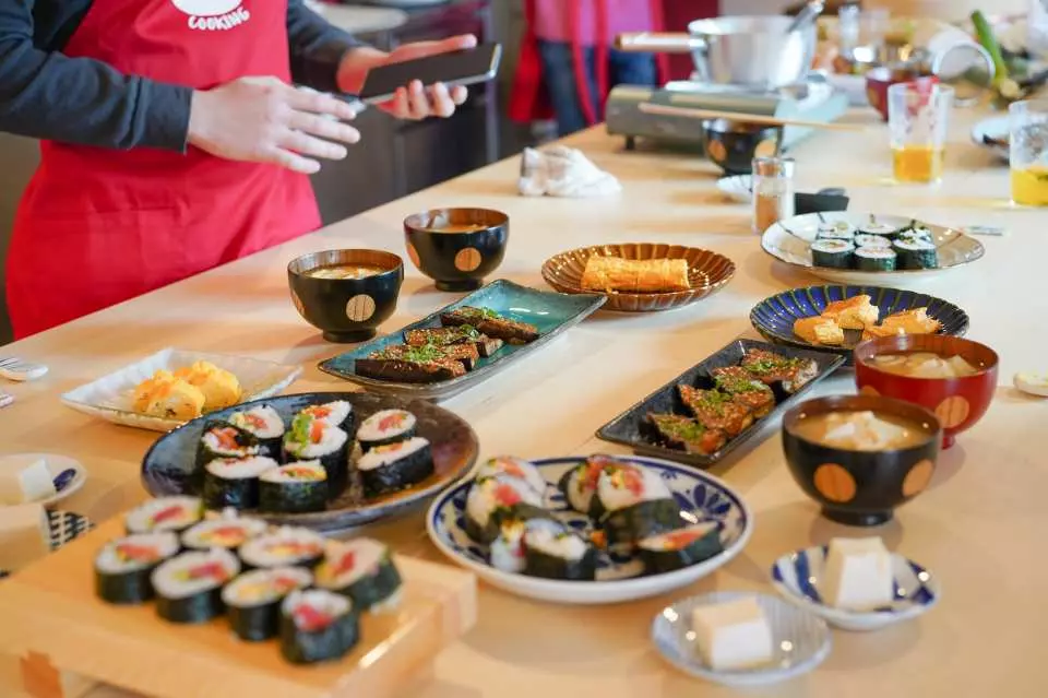 A lavish meal after the Tokyo sushi cooking class, with the table laden with various handmade sushi rolls, miso soup, tamagoyaki, and grilled eggplant, all prepared by the participants, ready for tasting.