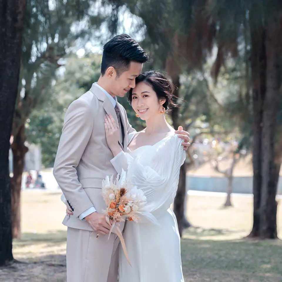冲绳轻婚纱拍摄，情侣在绿树林间甜蜜相拥，新娘手持捧花对镜头灿笑，留下永恆爱恋印记。