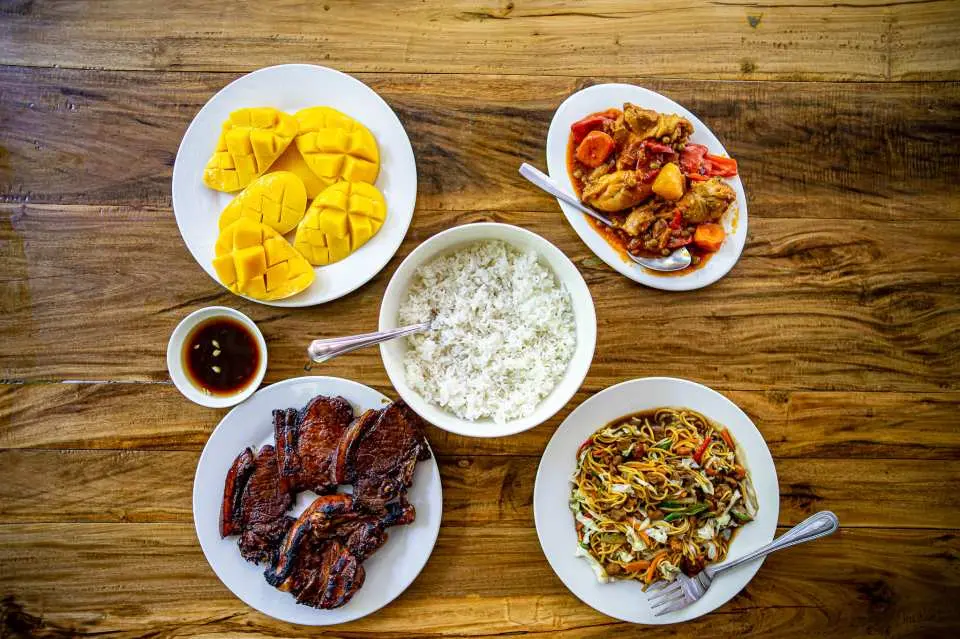 丰富美味的菲律宾午餐，包含烤猪肉、米饭、新鲜芒果、面条和炖鸡，为卡瓦山瀑布和墨宝之旅的一部分。