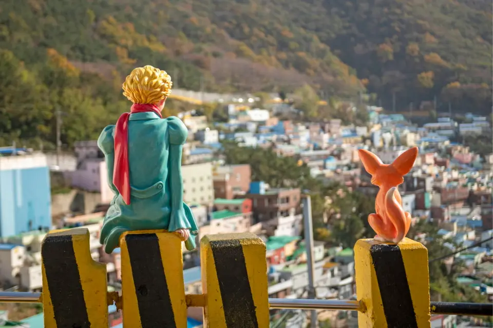 The iconic Little Prince and Fox statues in Busan's Gamcheon Culture Village, overlooking the tiered colorful houses on the hillside, a popular photo spot.