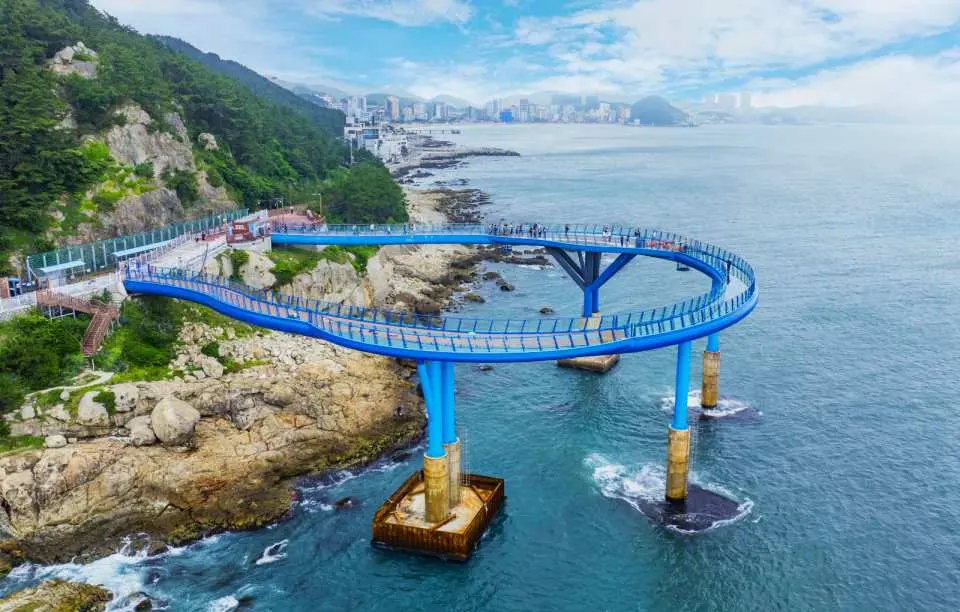 Busan's Oryukdo Skywalk, a U-shaped transparent glass walkway suspended over the deep blue sea, where visitors enjoy breathtaking panoramic ocean views.