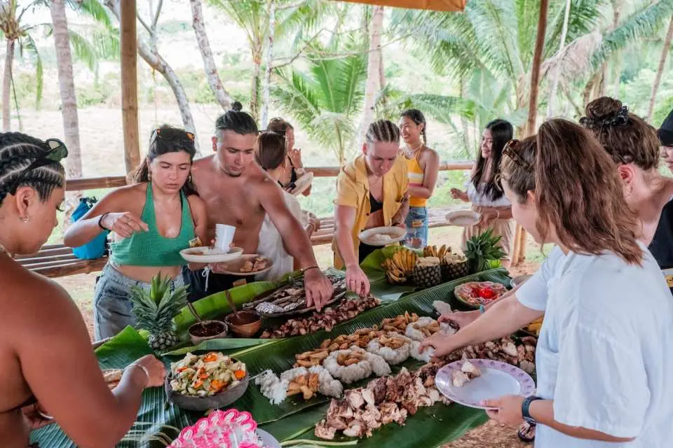 A lavish local lunch spread on banana leaves is enjoyed by travelers in El Nido's countryside, a unique cultural experience of the jeepney tour in Palawan.